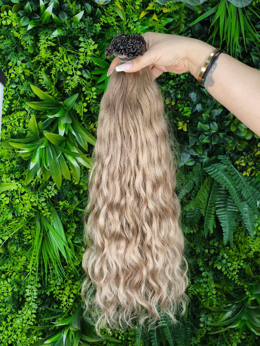 Virgin Echthaar Bondings Balayage Blond 61 cm auf grünem Hintergrund mit Wellenstruktur